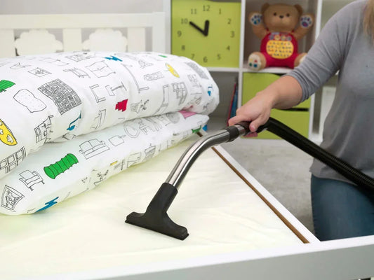 Vacuuming a child's crib mattress with a crevice tool to remove dust mites 
