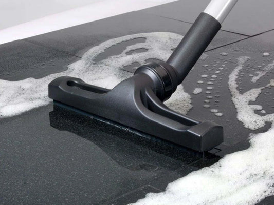 A wet vacuum floor attachment being dragged across a wet, soapy floor.
