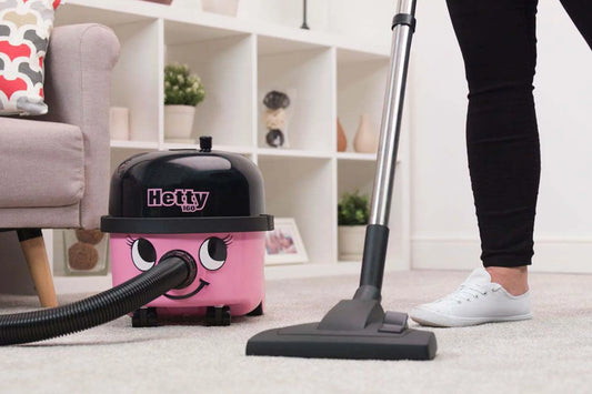A person vacuuming a carpet using Hetty 200 